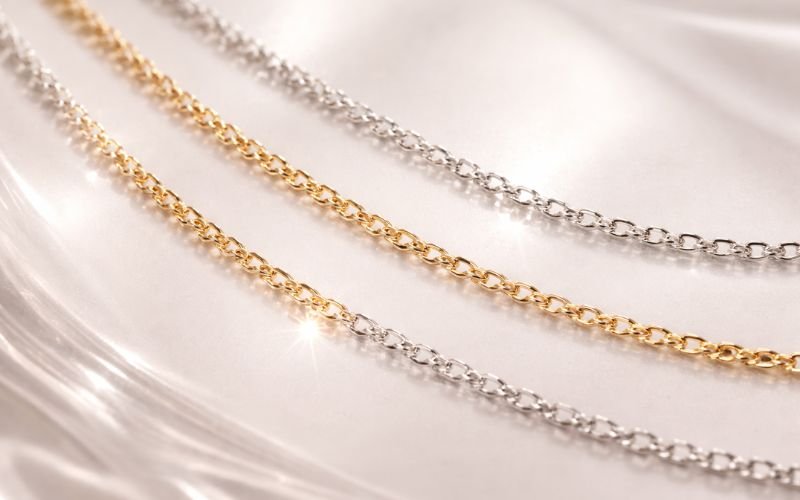 Gold, silver, and platinum permanent jewelry pieces side by side
