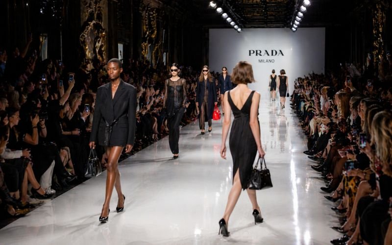 Modern runway fashion show with models showcasing luxury designer outfits on stage
