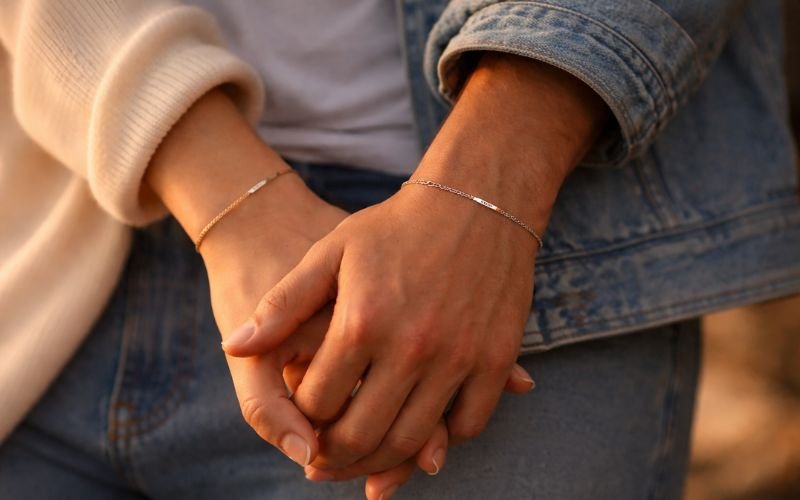 Couple wearing minimalist permanent bracelets on intertwined hands
