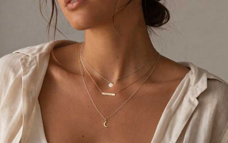 Model wearing multiple layered permanent necklaces for a chic look
