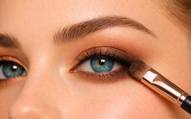 Applying matte brown eyeshadow on blue eyes with blending brush